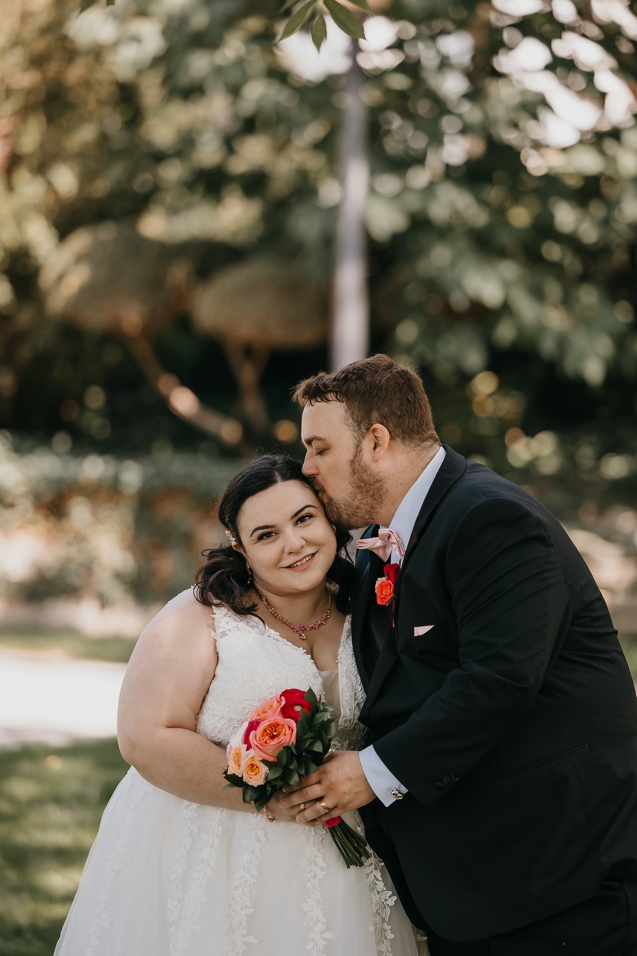 Greg kissing Chelsie on the forehead while she holds her bouquet