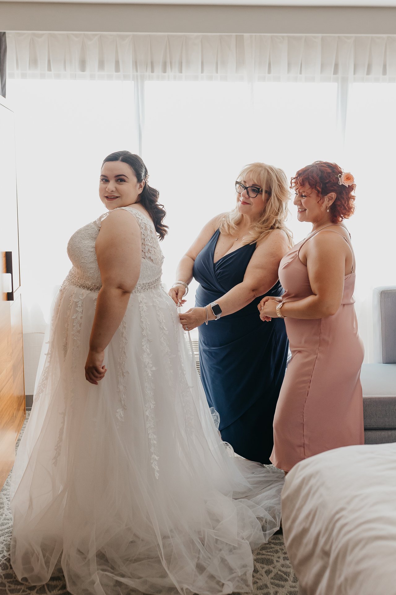 Chelsie in her wedding dress with family helping her get ready